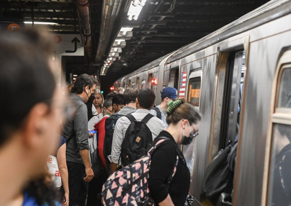 People board a subway train.
