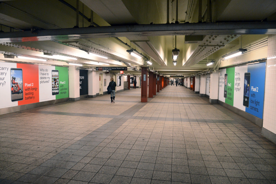 People walk down a passageway in the 42 St-Bryant Park subway station.